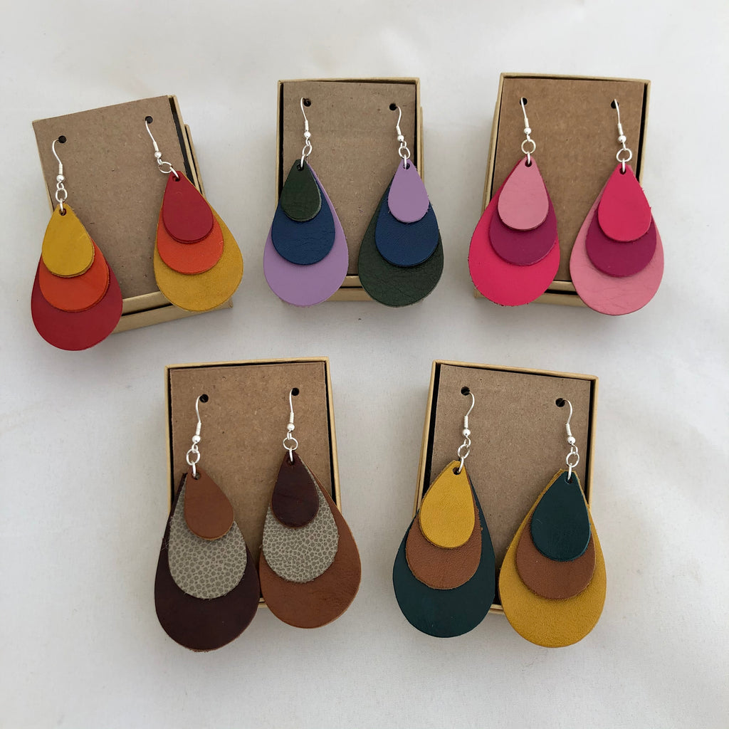 Tri Color Leather Rainbow Earrings in 5 color options: Red Orange Yellow, Lavender Blue Green, Shades of Pink, Shades of Brown, and Teal Brown Yellow. All earrings are pictured against a white background on brown cards in included jewelry boxes.