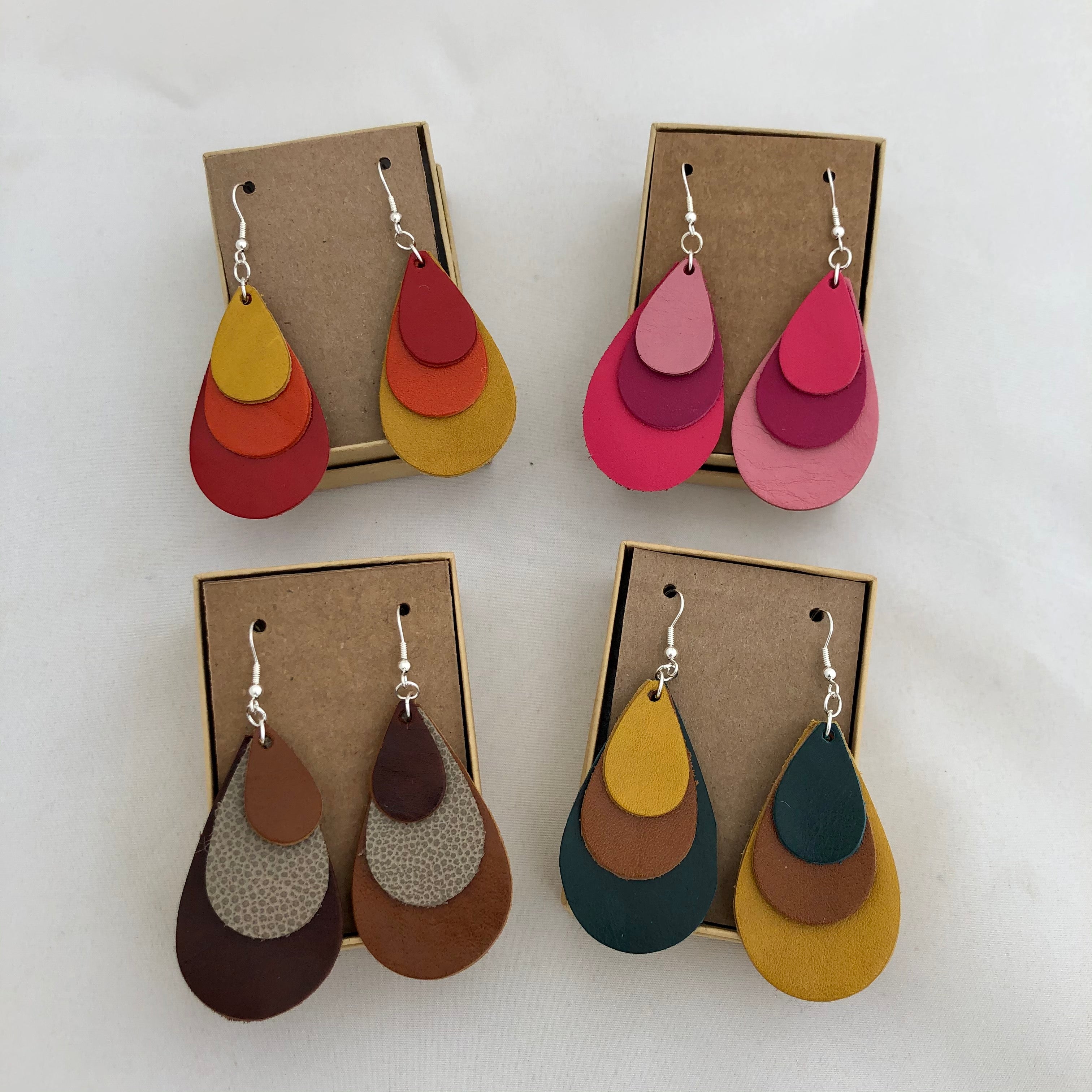 Tri Color Leather Rainbow Earrings in 4 color options: Red Orange Yellow, Shades of Pink, Shades of Brown, and Teal Brown Yellow. All earrings are pictured against a white background on brown cards in included jewelry boxes.