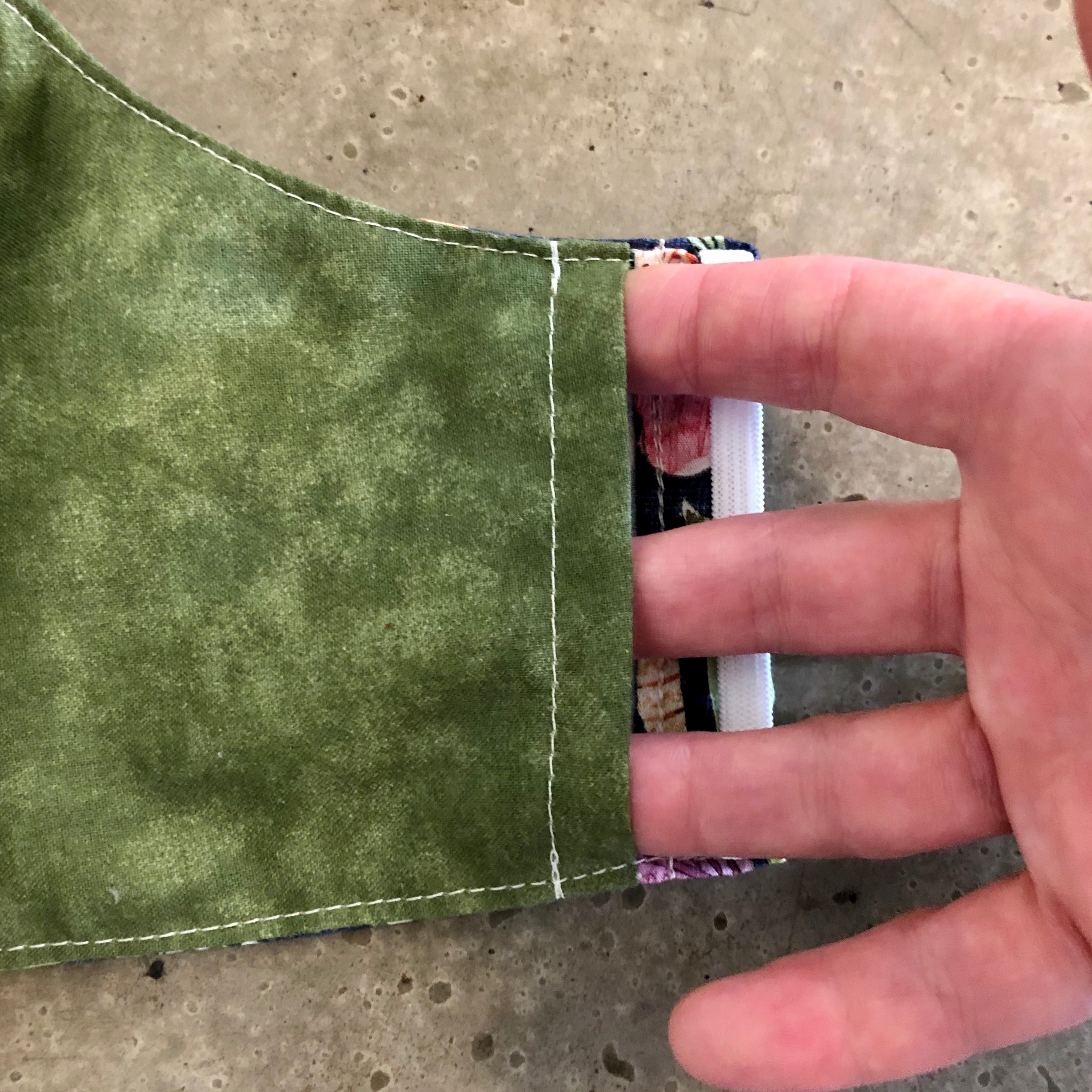 This is a close up of the inside of the fresh vegetable face mask, showing the olive green fabric and the opening to the right side of the filter pocket. There is an identical opening on the left side.